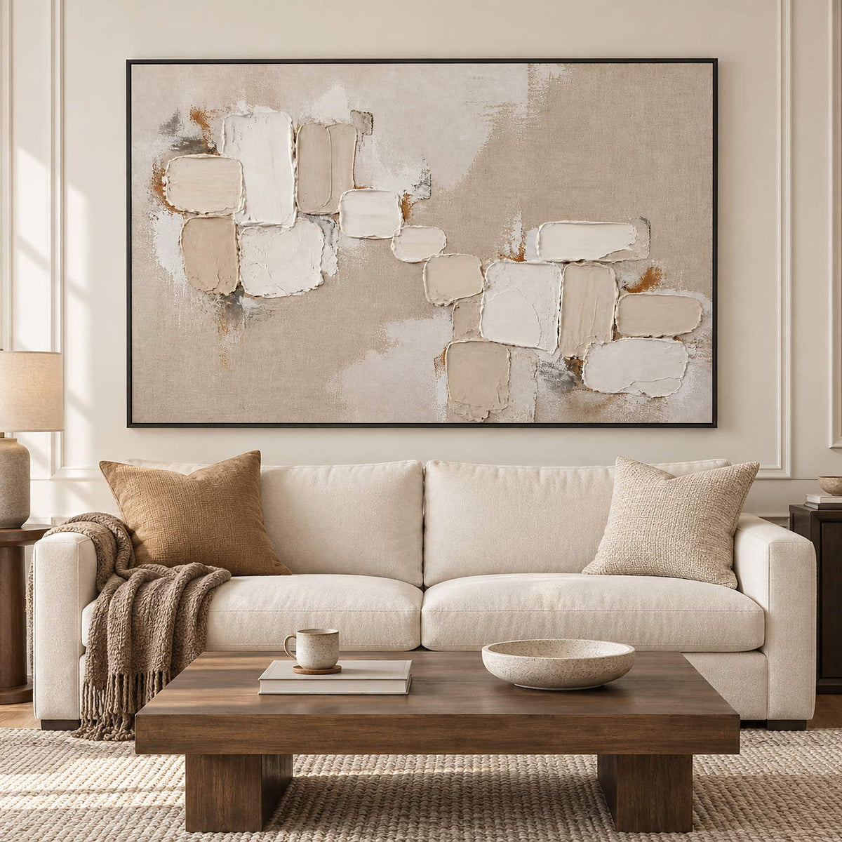 Textured abstract painting with raised ivory and taupe blocks in a black frame in a living room.