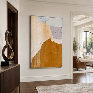Silver framed warm abstract artwork beside a sculptural bronze ornament in a residential entryway.