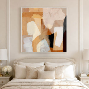 Pale-framed warm abstract painting centered above a bed with cream cushions.
