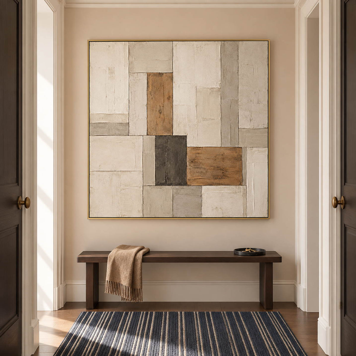 Textured ivory stone caramel and charcoal blocks in a quiet square composition, displayed in a hallway in a gold frame.