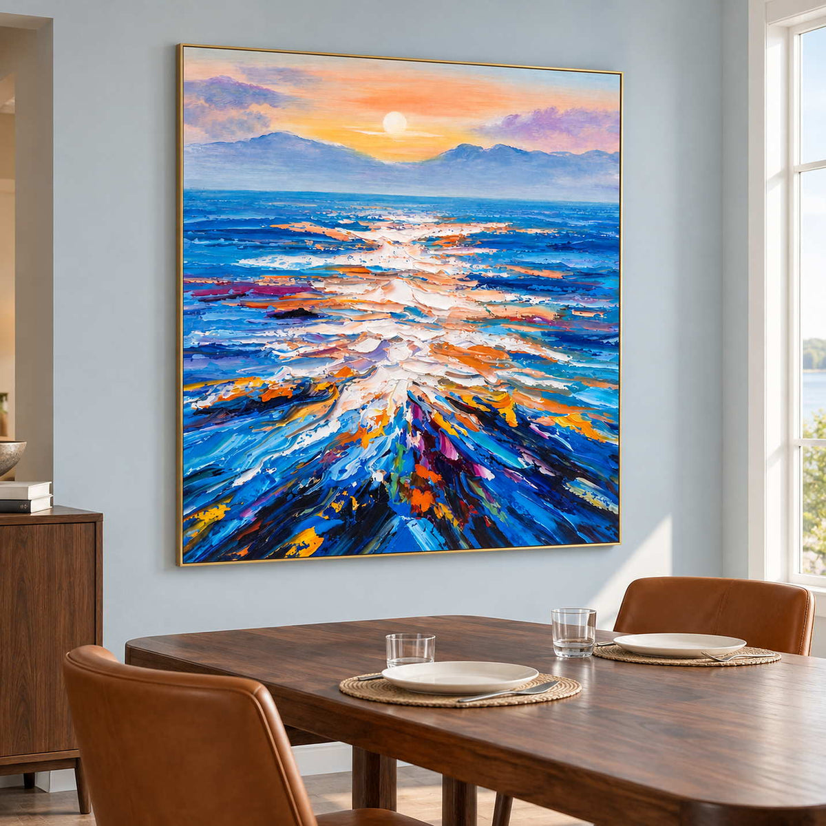 Sunlit sea artwork on a pale blue wall beside a wooden dining table and brown chairs.