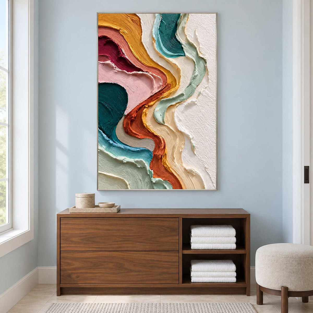 Tall abstract on a pale blue wall above a towel cabinet.