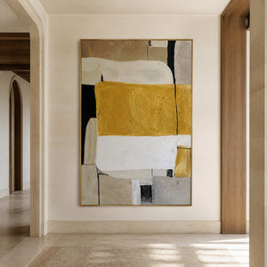 Gold framed abstract painting with ochre and cream blocks in a sunlit hallway.
