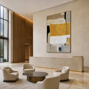 Large gold framed ochre abstract painting overlooking a refined hotel seating area.
