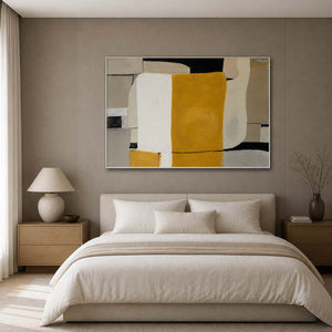White framed horizontal abstract painting bringing ochre warmth above a softly upholstered bed.