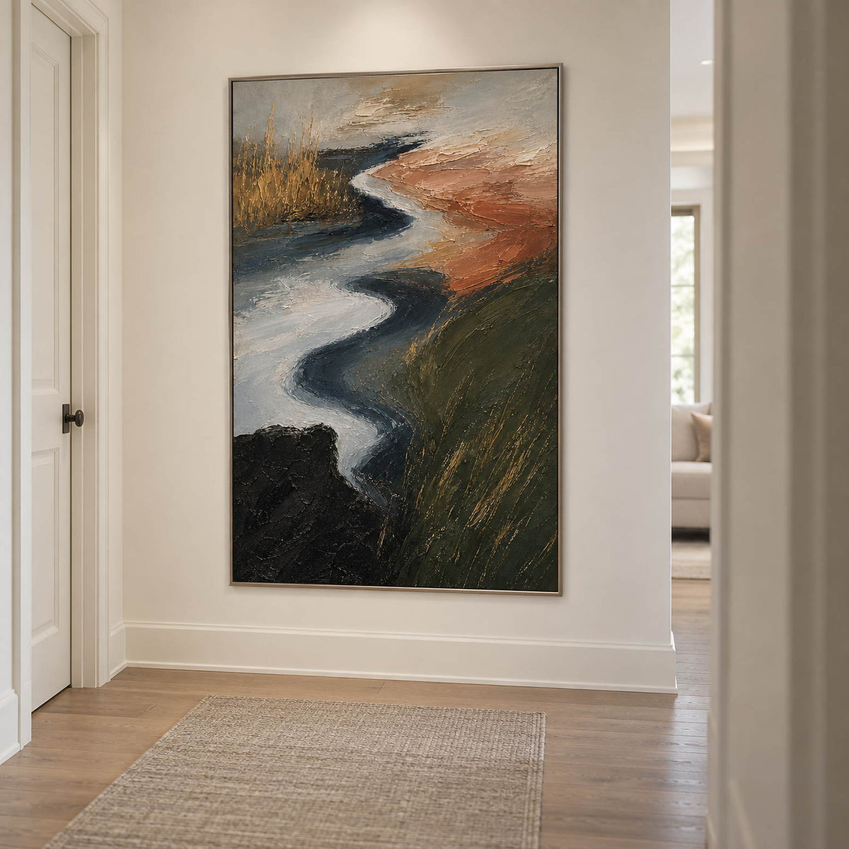 A winding pale waterway between dark green and rust-colored fields in a silver frame, displayed in a hallway.