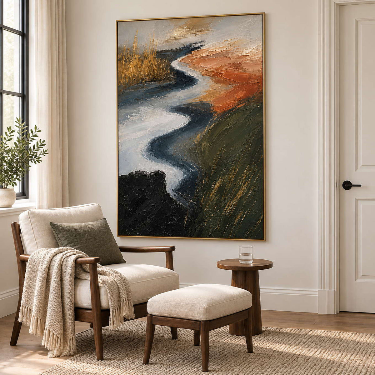 A winding pale waterway between dark green and rust-colored fields in a gold frame, displayed beside seating in a lounge.