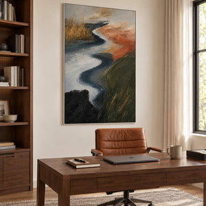 A winding pale waterway between dark green and rust-colored fields in a white frame, displayed in a home office.