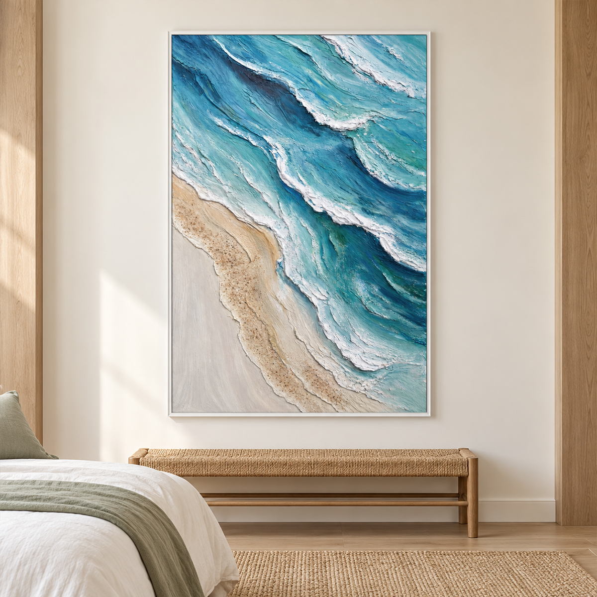 In a bedroom near the bed, an artwork with a white frame shows layered blue-green waves with raised white edges beside a pale sandy shore.