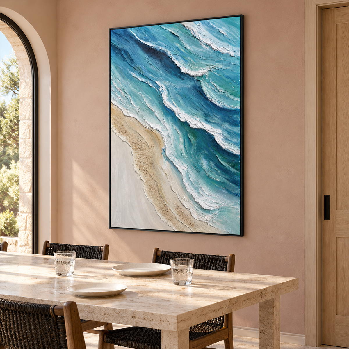 In a dining area beside the table, an artwork with a black frame shows layered blue-green waves with raised white edges beside a pale sandy shore.
