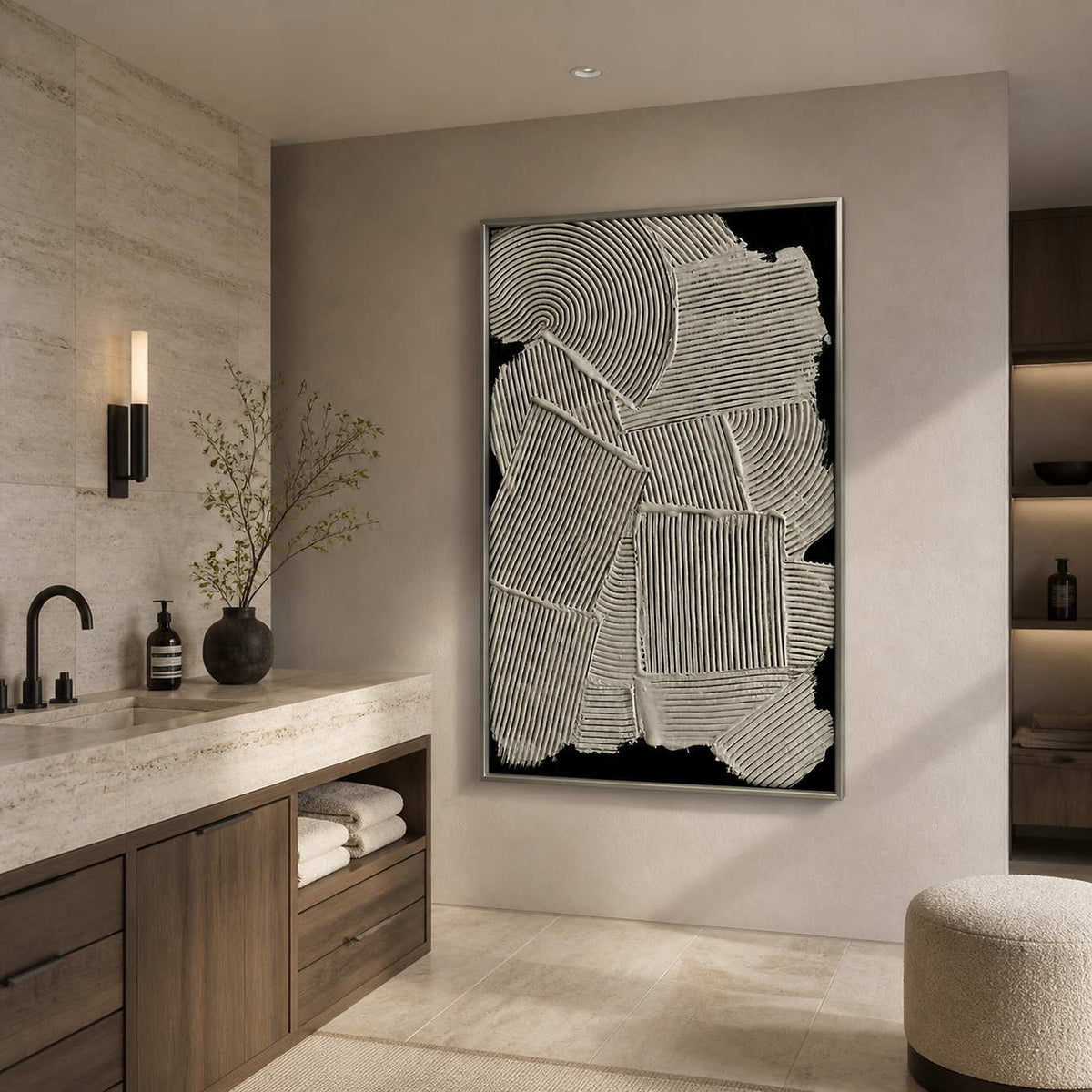 Silver framed ribbed abstract artwork beside a pale stone vanity in a bathroom dry area.