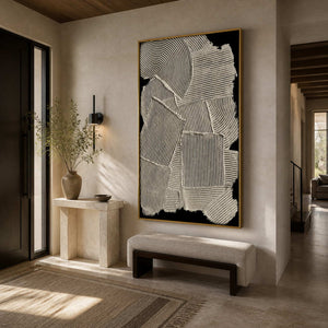 Gold framed cream relief artwork above a cushioned entryway bench beside a small stone console.