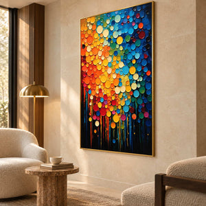 Multicolored circle painting beside a rounded cream chair and small textured side table.