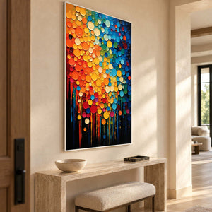 Color-dot artwork above a pale console with an upholstered stool in an entryway.