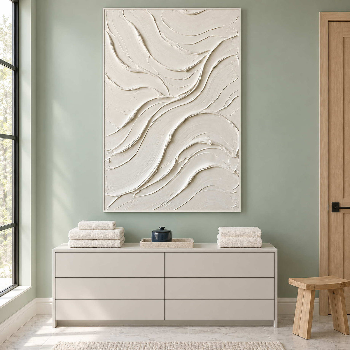 Tall ivory artwork above a white cabinet with towels.