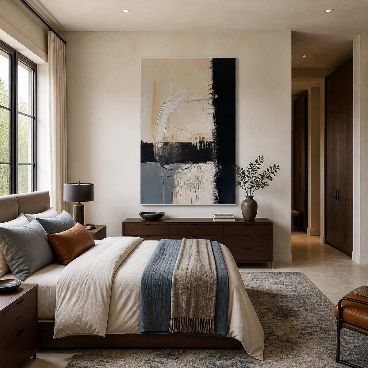 White-framed neutral and blue abstract art above a wood dresser beside a bed with a blue throw.