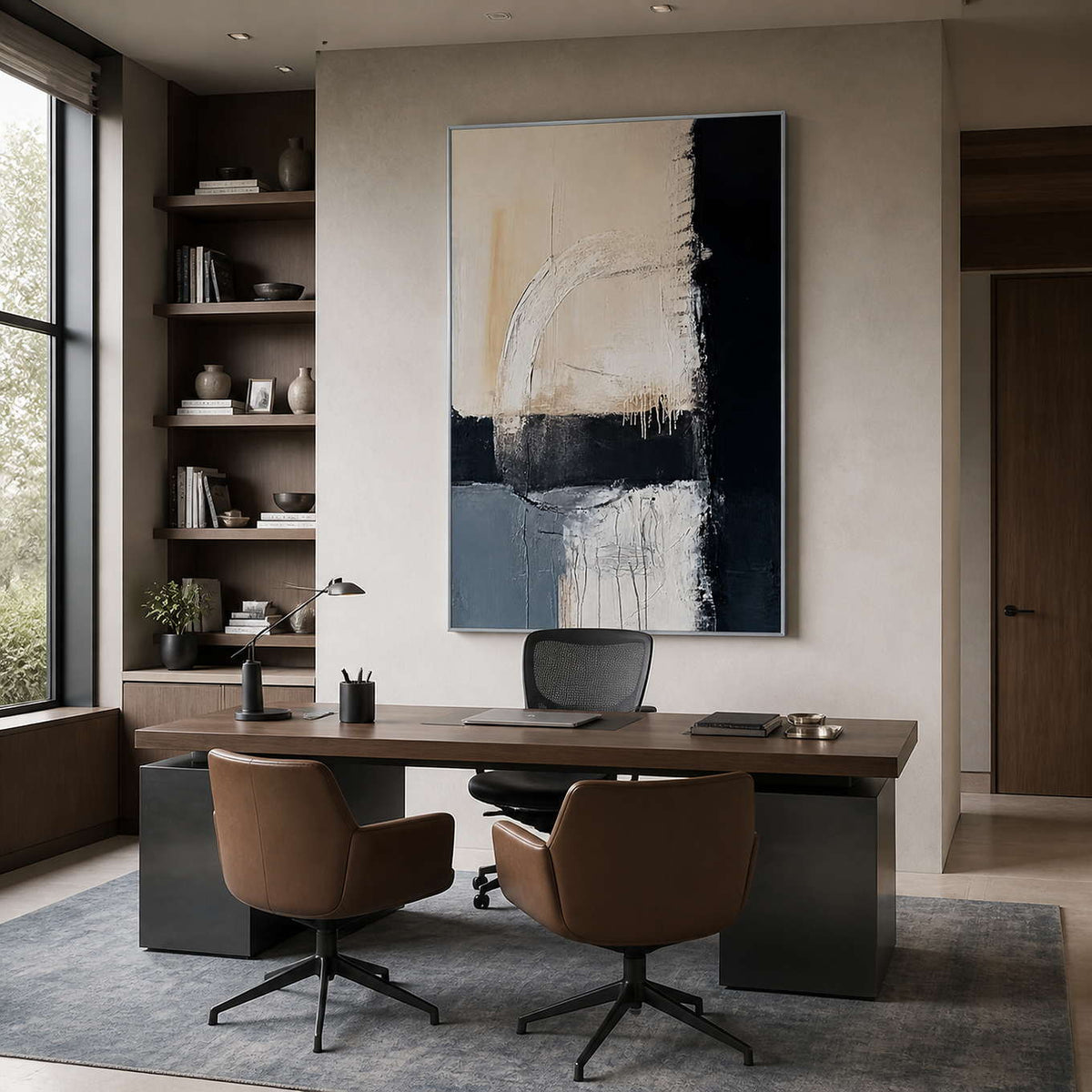 Silver-framed vertical abstract painting behind an office desk with brown leather guest chairs and dark bookshelves.