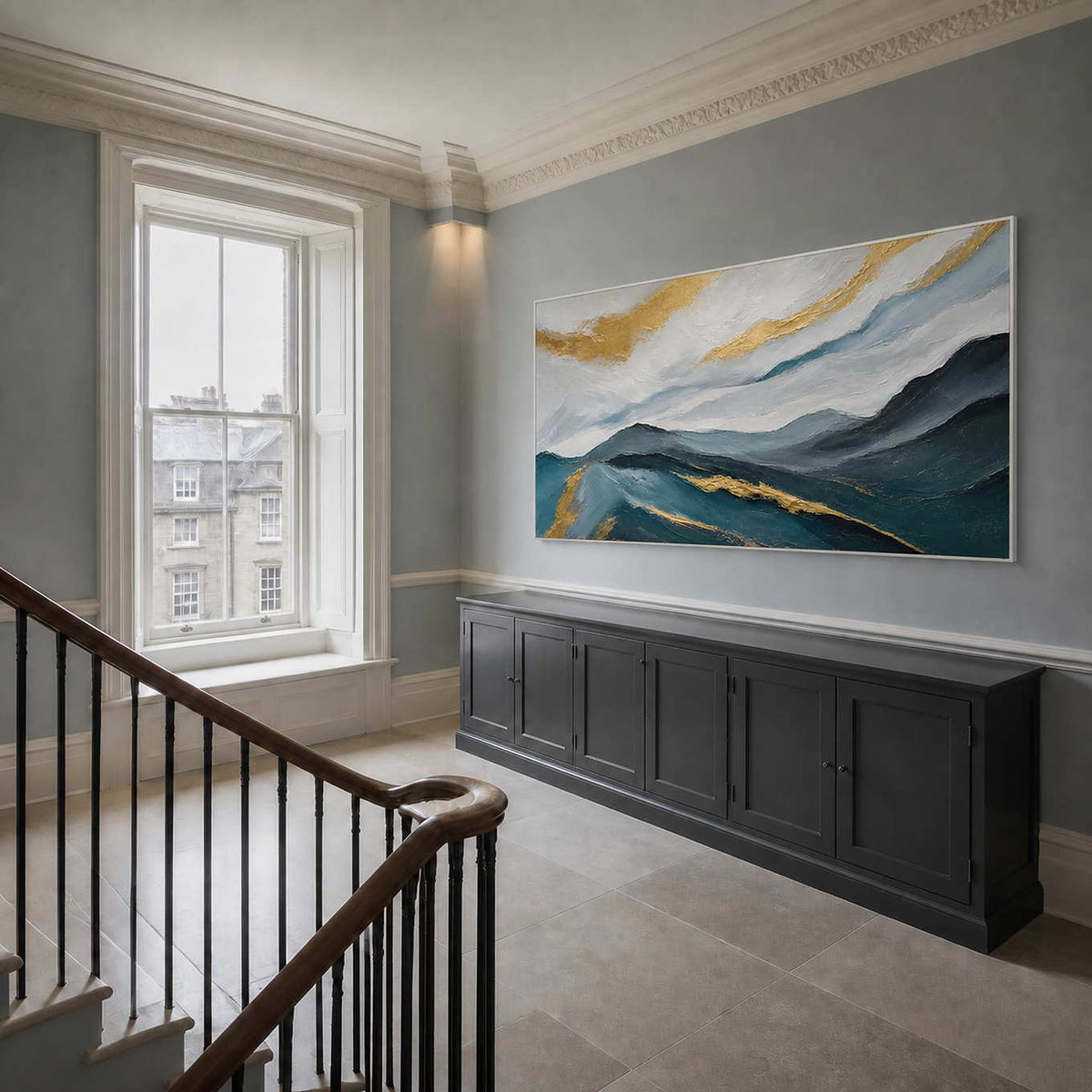 Panoramic mountain artwork styled beside a staircase in a bright entryway.