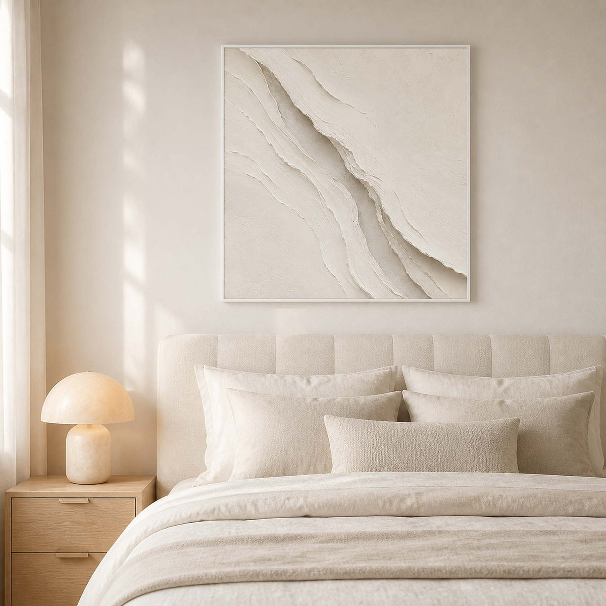 Textured neutral wall art displayed in a warm white minimalist bedroom.