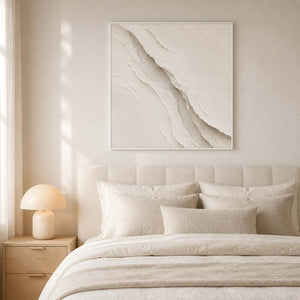 Textured neutral wall art displayed in a warm white minimalist bedroom.