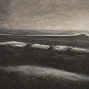 Close-up of charcoal shoreline ivory surf and layered gray texture.
