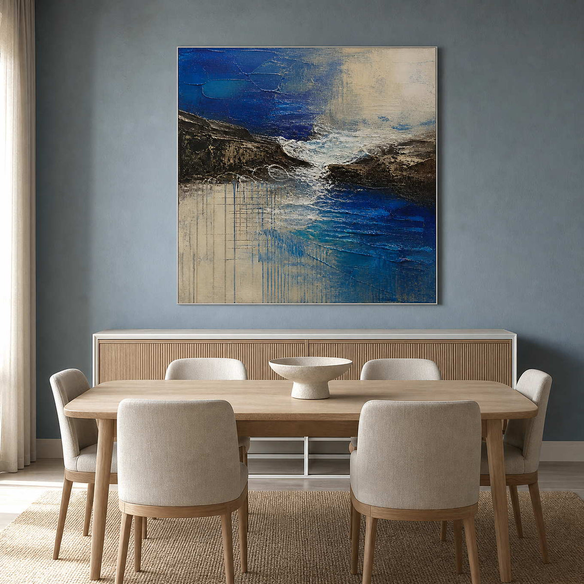 Blue and ivory coastal abstract painting in a bright dining room.