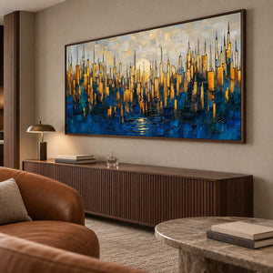 Wide city painting above a ribbed dark wood cabinet beside brown leather seating.