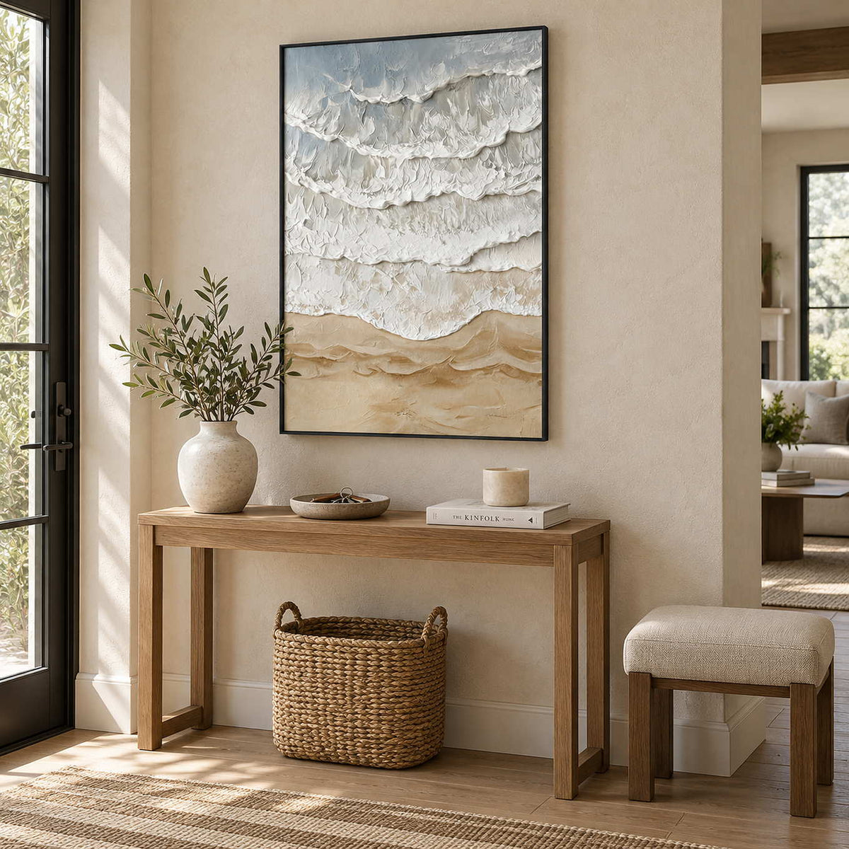 Whispering Tides in a black frame above a light wood hallway console with a basket and cream stool.