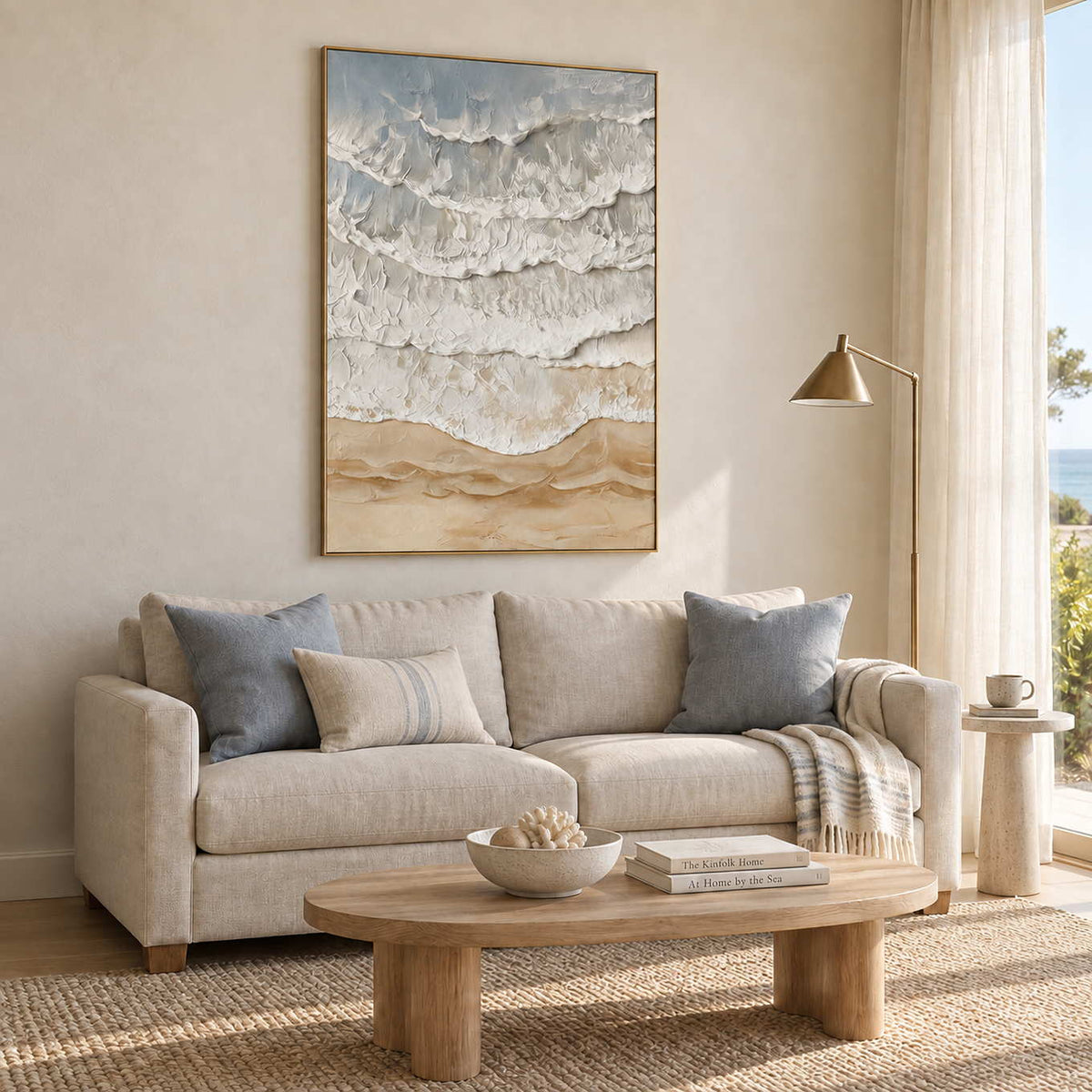 Whispering Tides in a gold frame above a cream sofa with blue-gray cushions beside a sunny window.