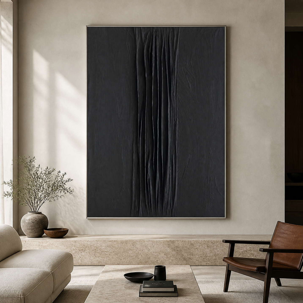 Silver framed black textured painting between a sofa and leather chair in a living room.