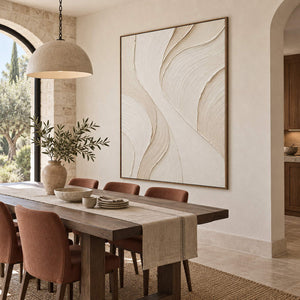 Hand-painted ivory abstract wall art with flowing cream relief and fine combed texture, displayed in a dining room in a brown wood frame.