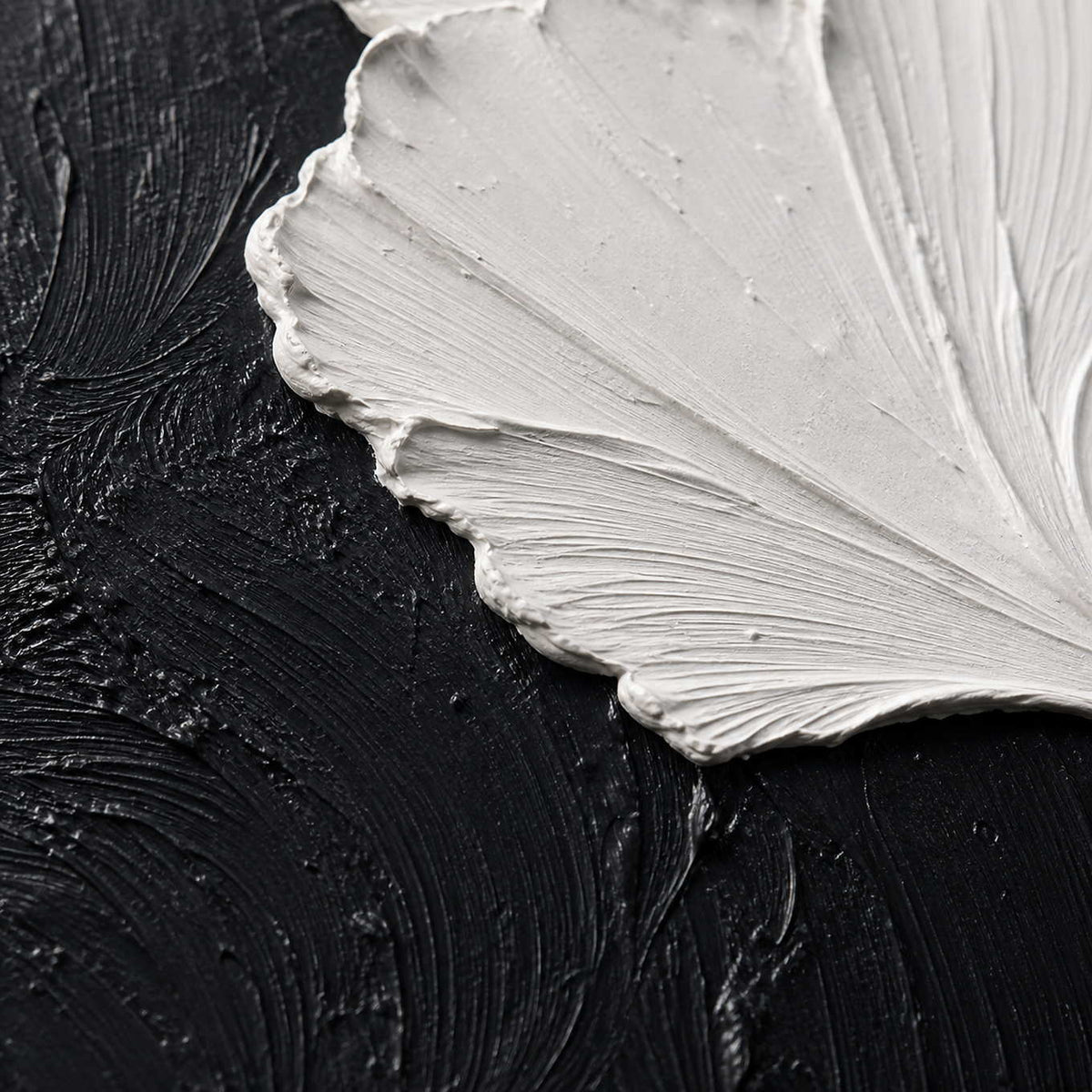 Close-up of raised white leaf texture against layered black paint.
