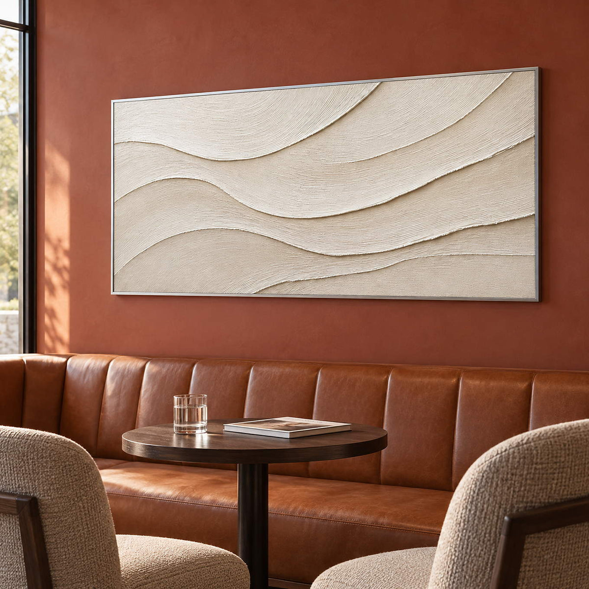 Layered ivory and warm beige relief flowing in quiet panoramic waves, displayed in a lounge in a silver frame.