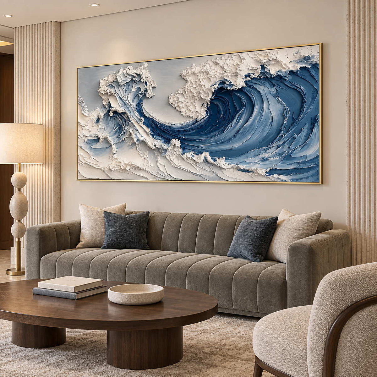 Gold-toned framed wave artwork above a gray sofa with blue and cream cushions.
