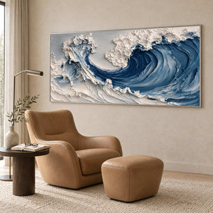 Blue wave painting beside a tan lounge chair, matching ottoman, and reading lamp.