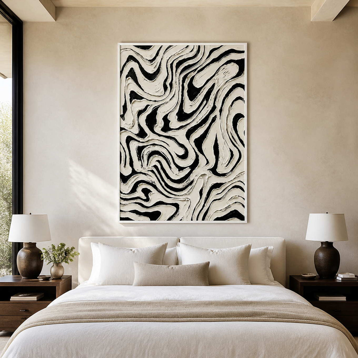 White framed black and white abstract painting with fluid lines above a bedroom headboard.