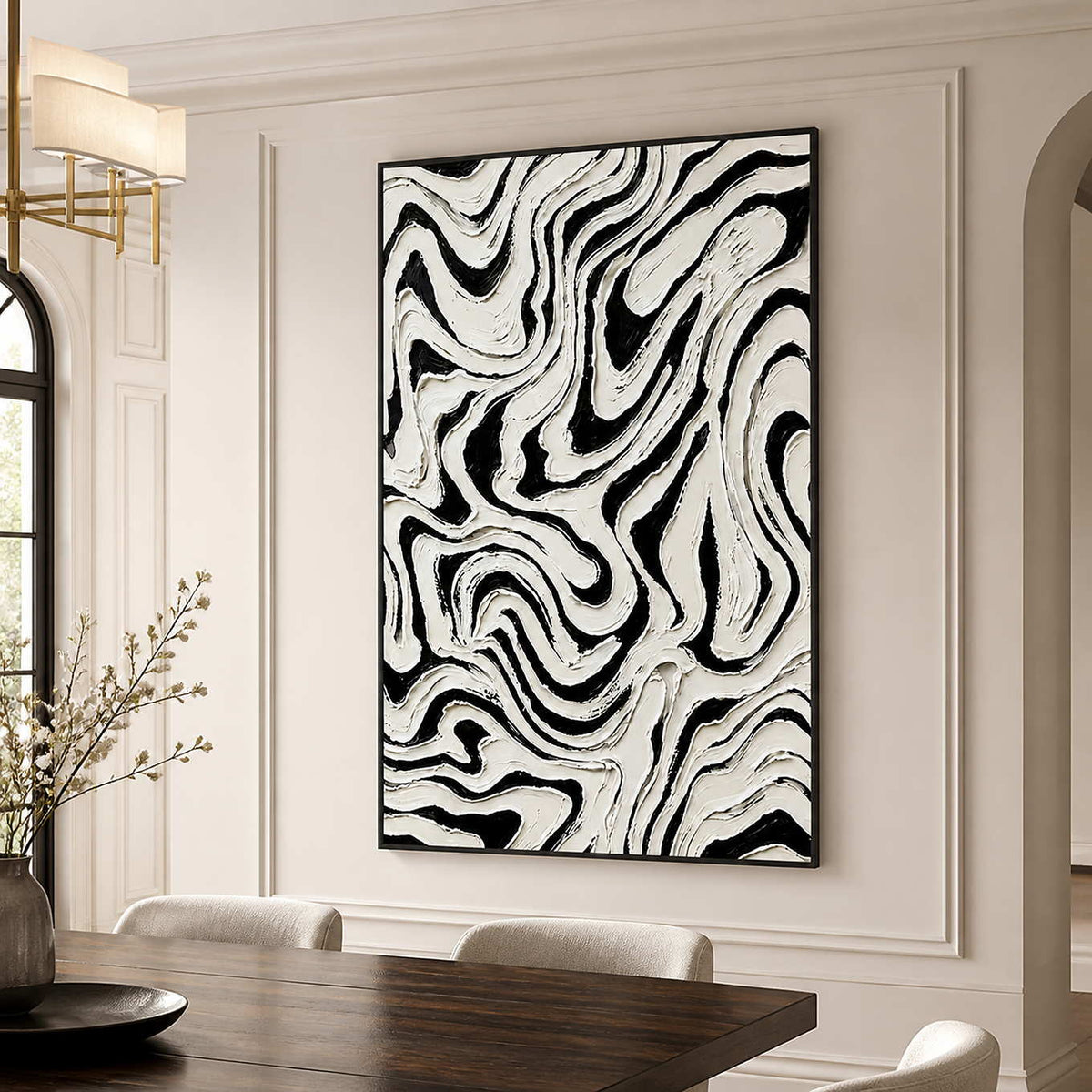 Black framed abstract artwork with swirling white ridges above a wooden dining table.