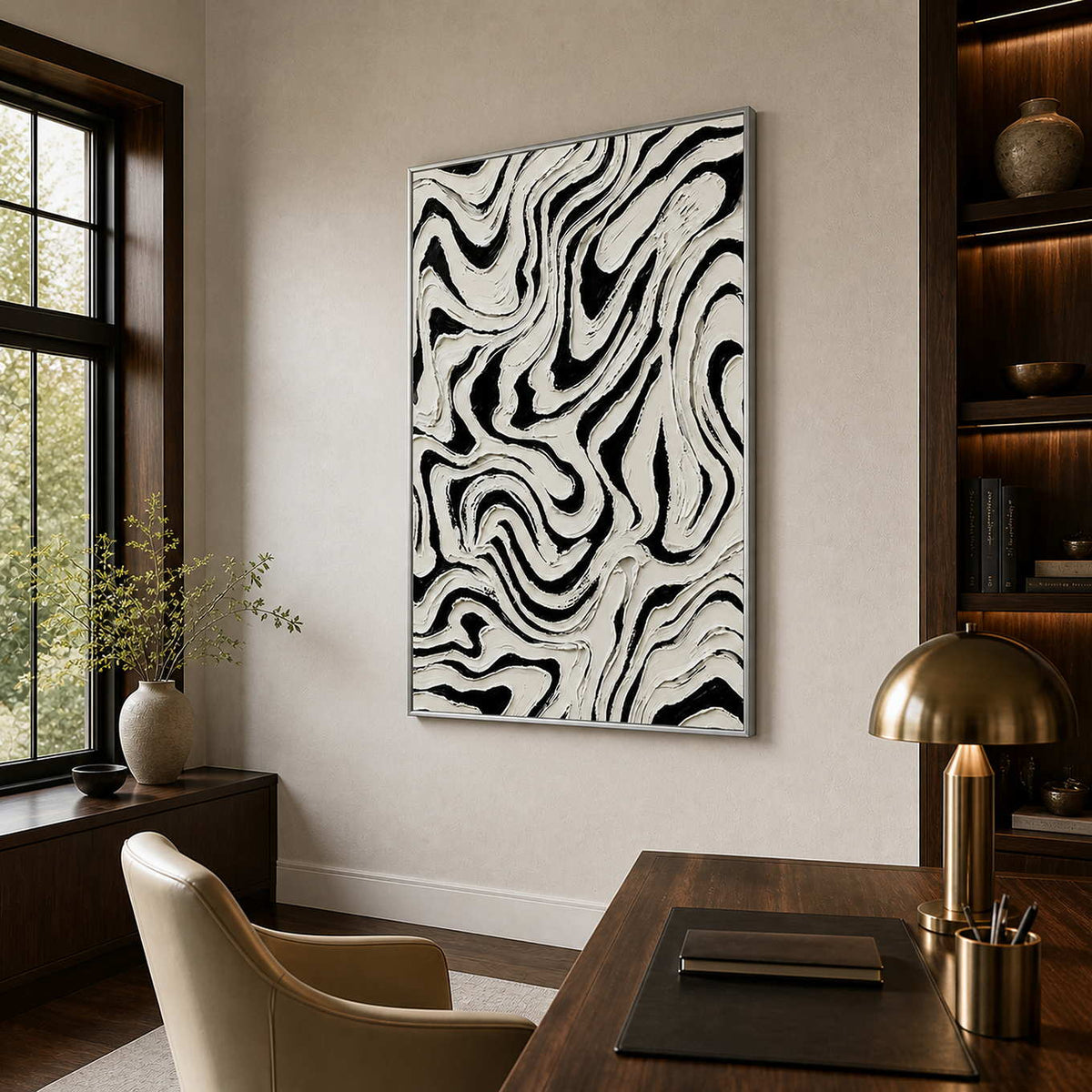 Silver framed monochrome abstract artwork with looping ridges beside an office bookshelf.