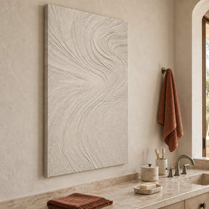 Ivory relief painting with fine flowing wave-like ridges without an outer frame beside a bathroom vanity.