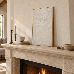 Ivory relief painting with fine flowing wave-like ridges in a gold frame resting on a fireplace mantel.
