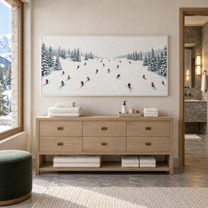 Winter Joy in a white frame above a light wood cabinet with folded towels beside a bathroom vanity.