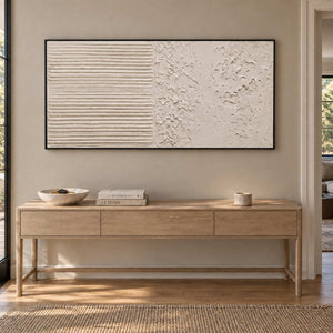 Wordless Dialogue in a black frame above a light wood hallway console with books, a bowl and a small cup.