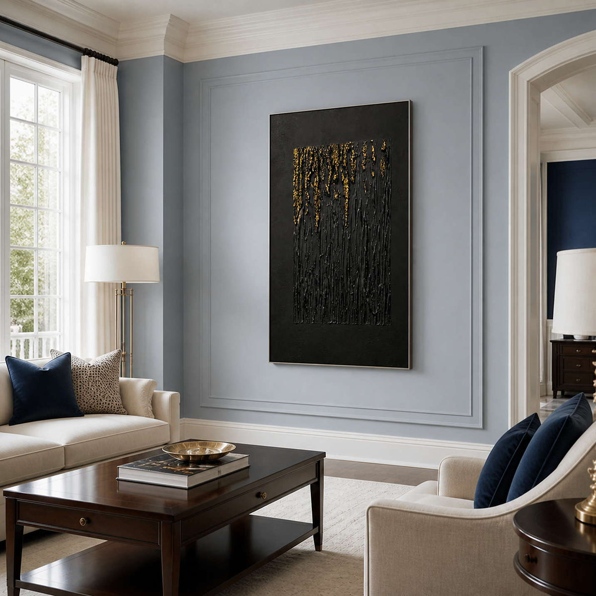Silver framed black and gold textured artwork in a sitting room with blue gray walls.