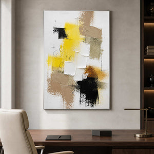 Yellow black and neutral abstract art displayed above a modern office desk.